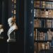 Dark library with statues on the ends of bookshelf rows
